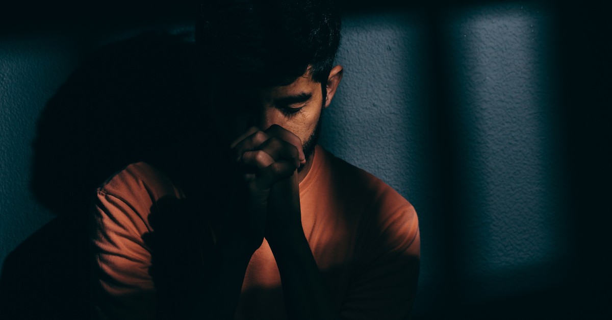 A man wearing orange and praying