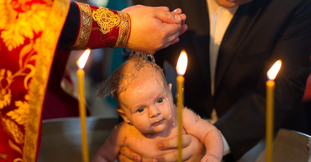 orthodox christian priest baptizing baby