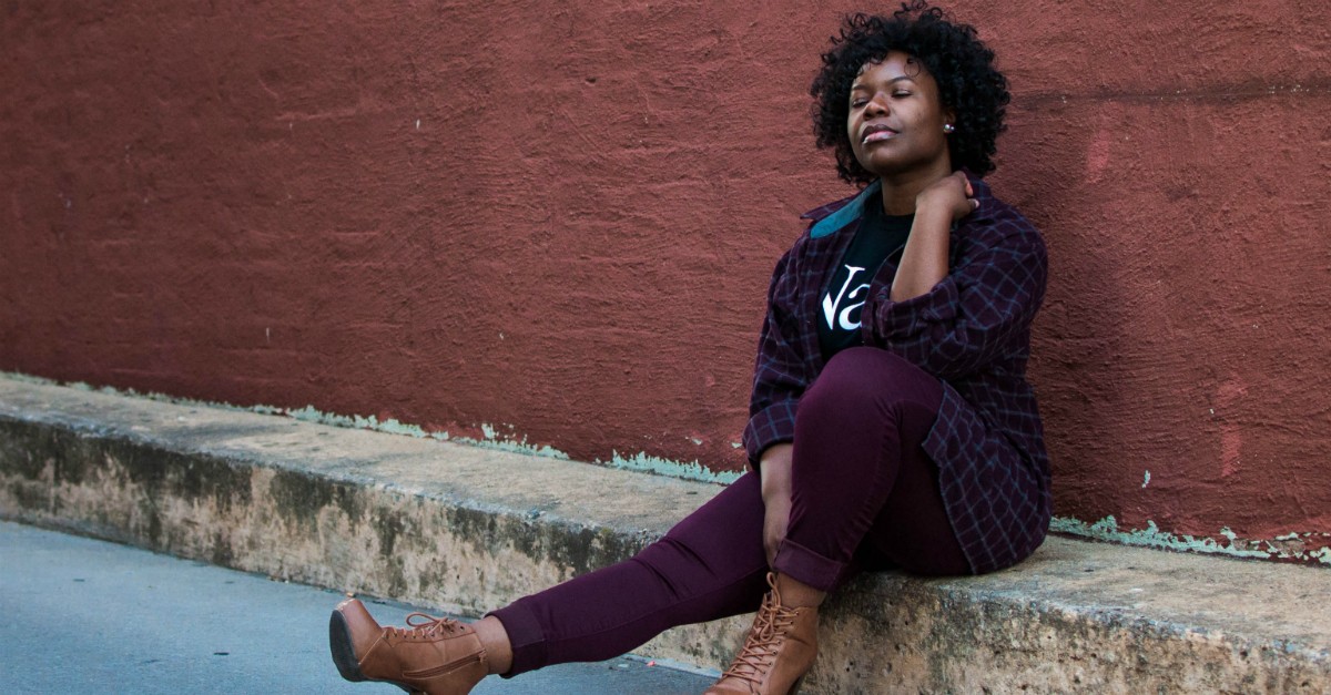 woman sitting on curb, eyes closed thinking or listening